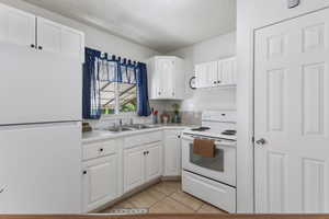 Kitchen with white appliances, white cabinetry, a textured ceiling, light countertops, and light tile patterned flooring