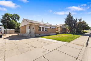 View of front of property with concrete driveway, brick siding, and a front lawn