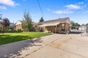 Rear view of house featuring brick siding, concrete driveway, an outbuilding, and a patio