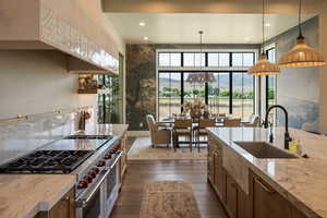 Kitchen featuring double oven range, a mountain view, decorative light fixtures, light stone counters, and brown cabinets