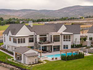 Back of property with a patio area, stucco siding, stone siding, a chimney, and a pool with connected hot tub