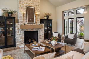 Living room with a fireplace, wood finished floors, and high vaulted ceiling