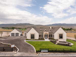 View of front of home featuring a mountain view, a fenced front yard, a chimney, asphalt driveway, and an attached garage