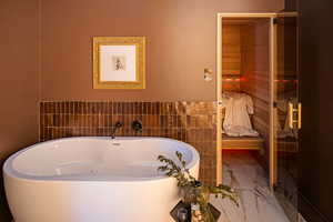 Full bath with a soaking tub, a sauna, tile walls, connected bathroom, and wainscoting