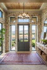 Doorway to outside with healthy amount of natural light, a mountain view, and wood ceiling