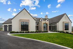 View of front facade with brick siding, a front yard, a chimney, and stone siding