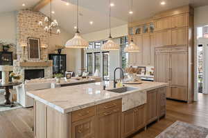 Kitchen featuring dark wood-type flooring, beam ceiling, glass insert cabinets, paneled fridge, and decorative light fixtures