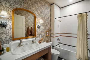 Full bathroom with shower / bathtub combination with curtain, vanity, and wallpapered walls