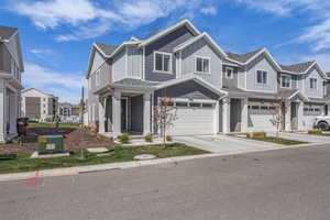 View of front facade with an attached garage, driveway, a residential view, board and batten siding, and roof with shingles