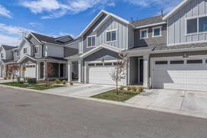 View of front of property with board and batten siding, a garage, concrete driveway, a residential view, and roof with shingles