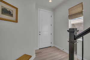 Foyer with recessed lighting, light wood finished floors, and stairway