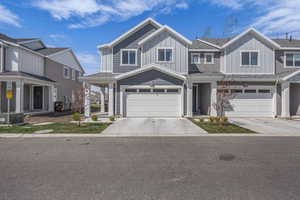View of front of home with an attached garage, concrete driveway, board and batten siding, and roof with shingles