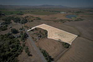 Aerial view of property and surrounding area featuring rural landscape, property boundaries highlighted, and mountains