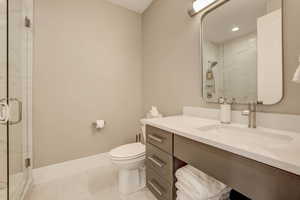 Full bath featuring a marble finish shower, vanity, light tile patterned flooring, and recessed lighting