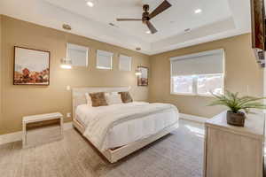 Carpeted bedroom with a tray ceiling, a ceiling fan, and recessed lighting