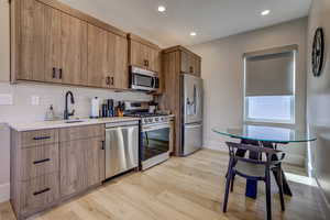 Kitchen featuring stainless steel appliances, backsplash, light wood finished floors, recessed lighting, and modern cabinets