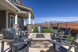 Fenced backyard featuring an outdoor fire pit, a patio area, a mountain view, and a ceiling fan