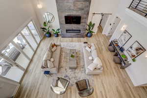 Living area with light wood-style floors, a towering ceiling, and a tiled fireplace