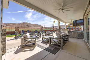 Fenced backyard featuring an outdoor kitchen, a patio area, a ceiling fan, and an outdoor living space