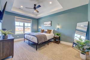 Bedroom with a raised ceiling, multiple windows, recessed lighting, and light carpet