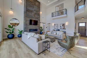 Living room featuring a barn door, a towering ceiling, light wood-style floors, and a large fireplace
