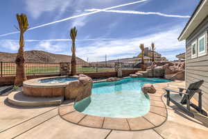 View of swimming pool with an in-ground hot tub, a patio area, a fenced backyard, and a mountain view
