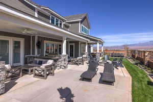 Fenced backyard featuring an outdoor living space with a fire pit, a patio area, a mountain view, and ceiling fan