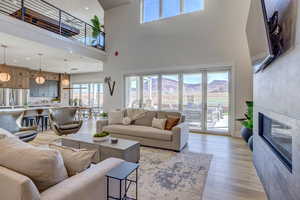 Living room featuring a tile fireplace, light wood finished floors, and a towering ceiling
