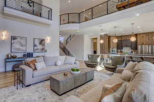 Living area featuring a high ceiling, light wood-style floors, recessed lighting, and stairway
