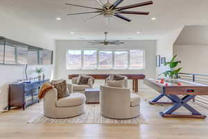 Living area with light wood-type flooring and recessed lighting