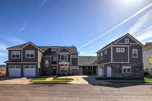 View of front of house featuring stone siding, concrete driveway, a garage, and board and batten siding