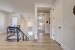 Hall with an upstairs landing, light wood-style flooring, and recessed lighting