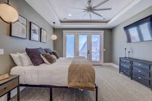 Bedroom with access to exterior, light carpet, ceiling fan, a raised ceiling, and french doors