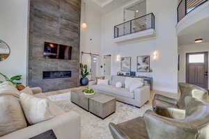Living room with a barn door, a tile fireplace, wood finished floors, and a high ceiling