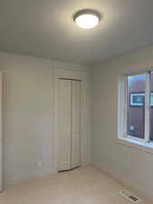 Unfurnished bedroom featuring a closet and light colored carpet
