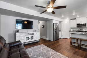 Living room with dark wood-style flooring, a ceiling fan, and recessed lighting