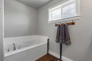 Full bathroom featuring a garden tub and dark wood-style floors