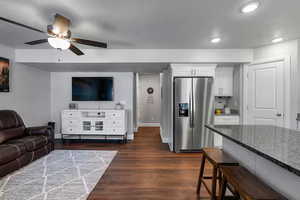 Living area with dark wood-style flooring, a ceiling fan, and recessed lighting