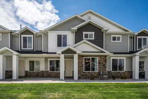 View of front of property featuring stone siding, a front yard, and board and batten siding