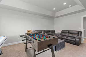 Playroom with light colored carpet, a tray ceiling, and recessed lighting