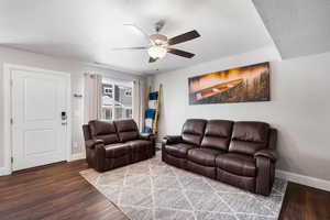 Living area with dark wood finished floors and ceiling fan