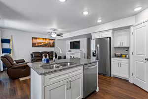Kitchen with open floor plan, white cabinetry, stainless steel appliances, dark wood finished floors, and recessed lighting