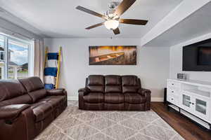 Living area featuring dark wood-type flooring and ceiling fan