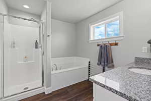 Bathroom with vanity, a shower stall, a bath, and dark wood-type flooring