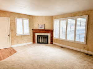 Living room featuring a fireplace, plantation shutters and carpet