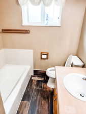 Upstairs bathroom: tub, vanity, and wood tiled floors