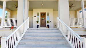 Property entrance featuring ceiling fan, covered porch, and stucco siding