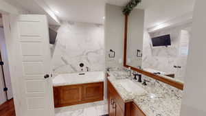 Bathroom with tile walls, vanity, a garden tub, light marble finish floors, and recessed lighting