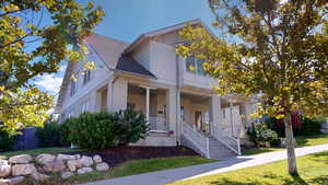 View of front of home with roof with shingles, a porch, a front yard, and stucco siding