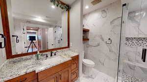 Bathroom featuring a marble finish shower, vanity, light marble finish flooring, and recessed lighting